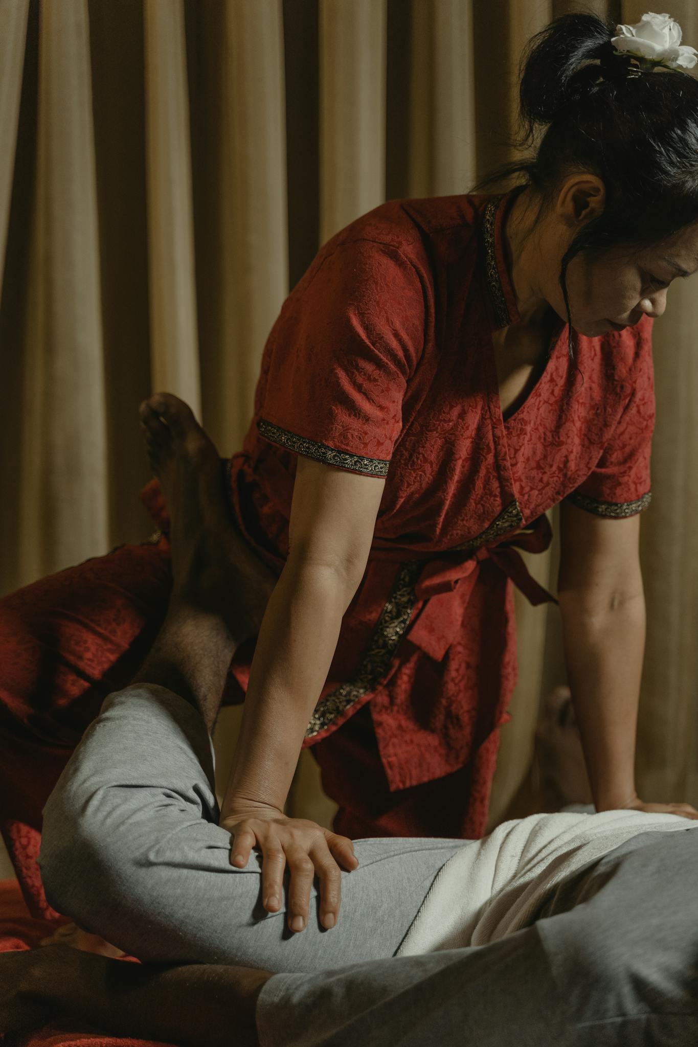Professional Thai massage session with therapist applying pressure on client's leg for relaxation.